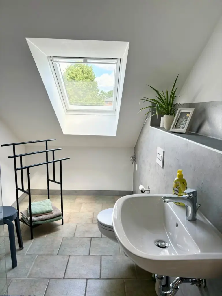 Waschbecken und WC im Duschbad unter dem Dachfenster