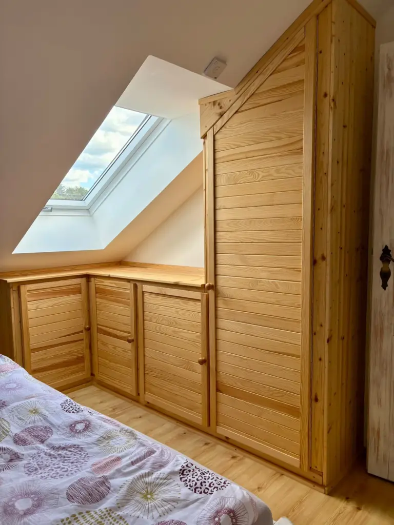 Kieferschrank und Bettende am Dachfenster im Schlafzimmer