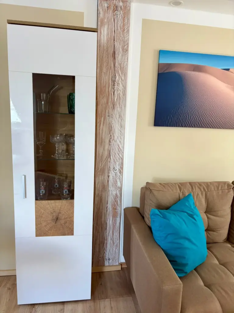 Vitrine mit Trinkglaesern neben dem Sofa